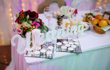 Wooden decor word wedding with candles on table