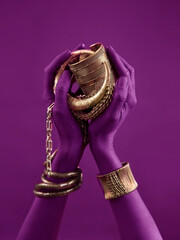 magenta woman's hands with gold jewelry. Oriental Bracelets on a black painted hand. Gold Jewelry