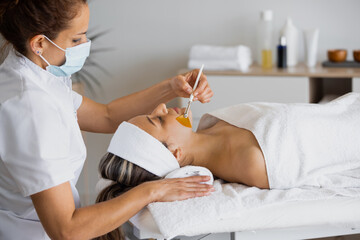 Cosmetologist with client during exfoliation procedure in spa salon