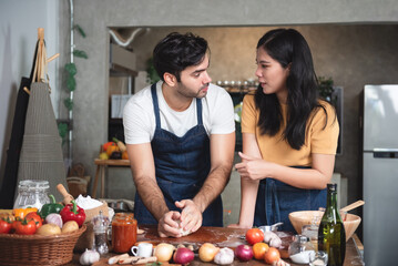 Young couple family caucasian man and asian women wearing aprons enjoy making pizza at home kitchen. Small business restaurant and cuisine.