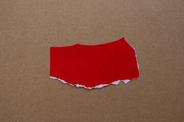 Blank torn paper isolated on cardboard background. Top view of red paper piece with copy space.