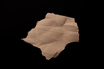 Blank torn cardboard isolated on black background. Top view of carton piece with copy space.