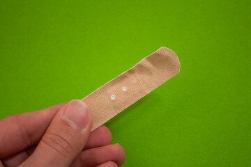 Hand holding adhesive plaster with copy space. Top view, close up.