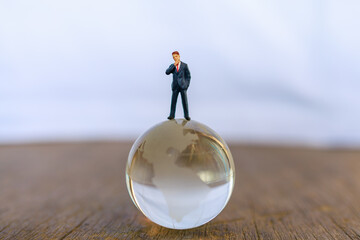 Global and Business Concept. Businessman miniature people figure standing on glass clear world ball model.