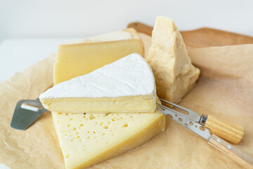 Different types of cheese lie on top of each other with cheese knives. A delicious delicacy.