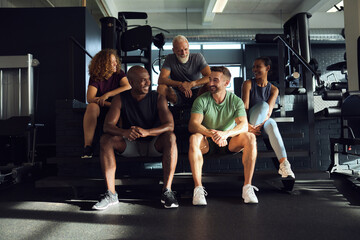 Smiling people sitting on steps at the gym