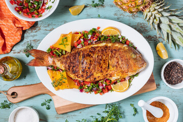 Red Snapper with ingredients. Prepared in tropical taste with Pico de Gallo and pineapple. Fresh and tasty fish and seafood.  - obrazy, fototapety, plakaty