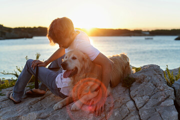 Handsome adult is enjoying the sunset with his dog together by the ocean. Golden Retriever and his...