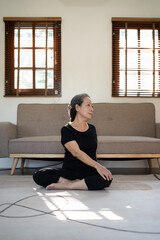 Fototapeta premium Home workout. Happy senior woman doing domestic training, exercise at home, indoors. Fit mature lady taking care of her body, leading active lifestyle.