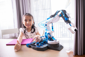 Asian little girl touching and playing a robotic machine arm.