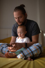 Dad and child are watching content on the phone.