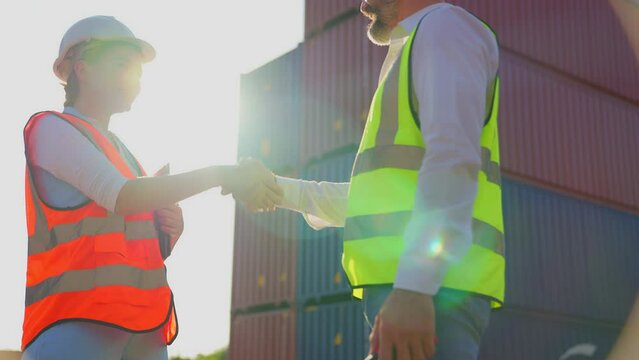 Female foreman and engineer worker man making shaking hands with partner in control loading containers box from cargo. Logistic import export and transport industry. making an agreement.