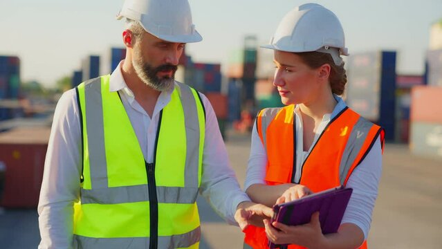 Two people of professional engineer have expertise worker in transport industry,wear safety vest, Work at container loading yard to inspect cargo loading process, Importing and exporting from abroad.