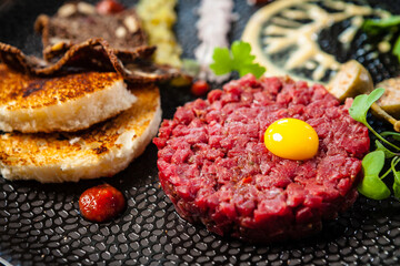 Beef tartare from Black Angus. Onion, quail egg, tomato sauce, mustard mayonnaise. Delicious healthy Italian traditional food closeup served for lunch in modern gourmet cuisine restaurant