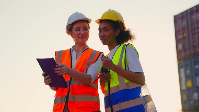 Two people of professional engineer have expertise worker in transport industry,wear safety vest, Work at container loading yard to inspect cargo process, Import and export from abroad checklist.