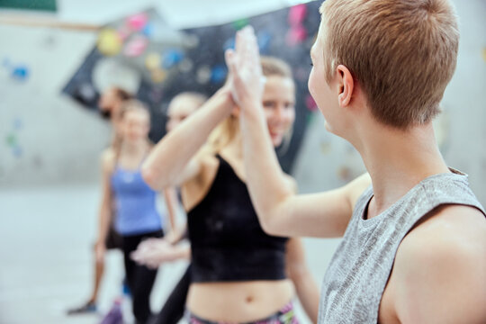 Smiling female friends high-fiving in a climbing gym