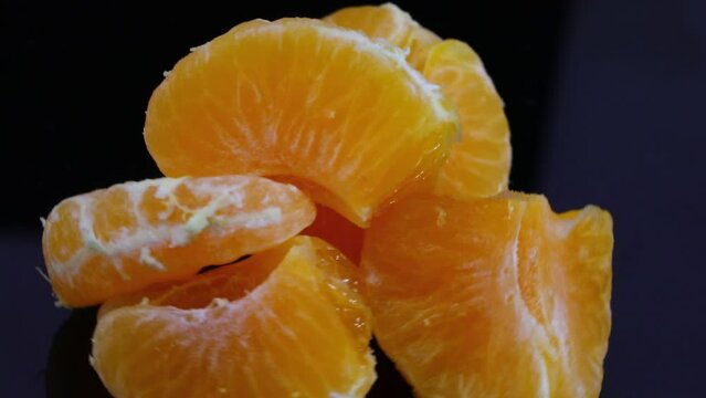 orange juicy clementine wedges spinning on black background
