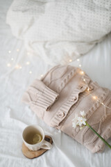 Knitted beige sweater and delicate spring flower. Winter and spring fashion concept. 