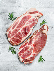 Raw pork steaks and fragrant rosemary.