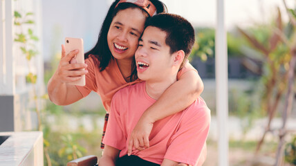 A smart young man with a disability smiling face using social media with parent to learning distance,Teenage boy use technology,social media,live,video chat,remote education,Homeschool Concept.