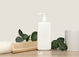 White towel wooden comb green eucalyptus branch. White shampoo.