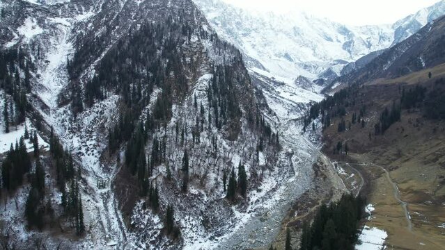 flying back aerial drone shot snow covered mountains with pine trees on hills with valley in between in himachal pradesh manali kullu showing the natural winter beauty of this hill station