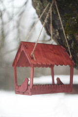 Close-up of a bird feeder on a tree under the snow in the forest.