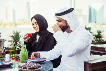 Happy couple spending time in Dubai. man and woman wearing traditional clothes having a conversation in a cafe