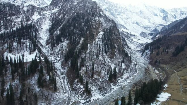 flying forward aerial drone shot snow covered mountains with pine trees on hills with valley in between in himachal pradesh manali kullu showing the natural winter beauty of this hill station