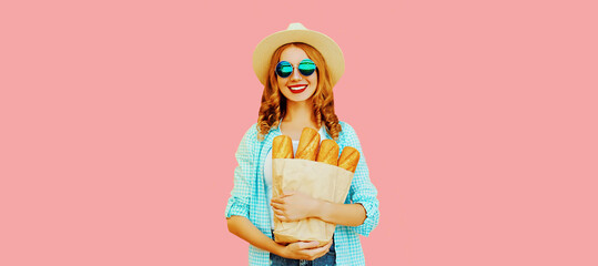 Portrait of happy smiling young woman holding grocery shopping paper bag with long white bread...