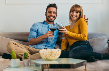 Young couple spending time together at home. Man and woman sitting on the couch and having fun