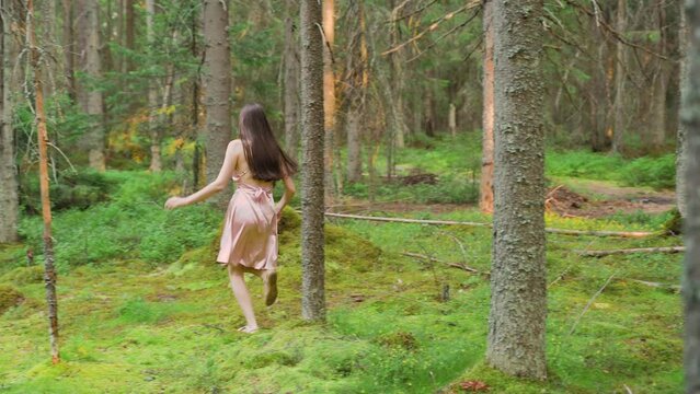 Girl in the forest runs around the pines