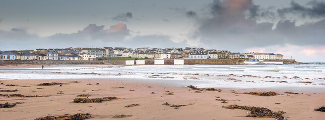 Panorama image of Kilkee beach and town house in the background. County Clare, Ireland. Nobody. Popular summer resort. Atlantic ocean, Irish seascape. Cloudy sky.