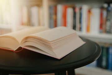 Open book on a black table. Library in the background. Book on table close up.