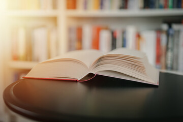 Open book on a black table. Library in the background. Book on table close up.