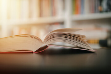Open book on a black table. Library in the background. Book on table close up.
