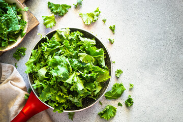 Kale salad leaves in the frying pan. Fresh green salad top view.
