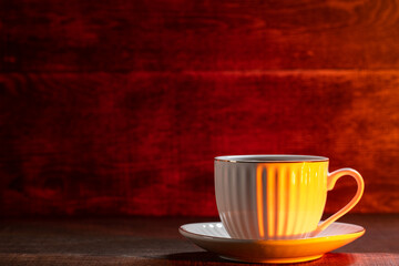 white cup of coffee or tea with a saucer on the table, wooden background copy space