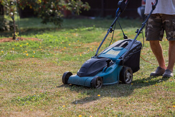 Obraz premium Banner. A human lawn mower cuts the grass in the backyard. Agricultural machinery for the care of the garden.