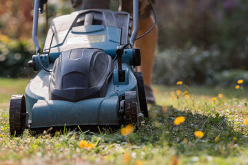 Fototapeta premium Banner. A human lawn mower cuts the grass in the backyard. Agricultural machinery for the care of the garden.