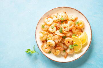 Shrimps with spices in craft plate at blue table. Top view with space for text.