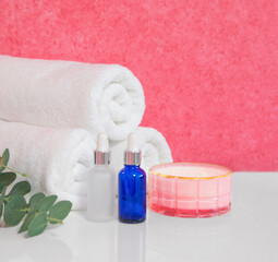 Fototapeta na wymiar Spa set of three white towels fragrant candle, eucalyptus branch, jars of oil on a light background