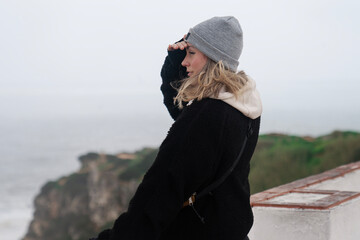 portrait of a woman standing on a view spot and watching the sea 