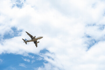 Fototapeta na wymiar landing plane on blue sky with clouds