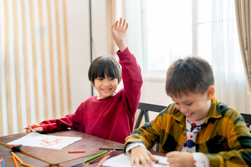 Asian boy raise his hand to ask questing in classroom and his friend look happy during work together.