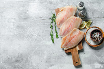 Fish fillet on a wooden cutting Board with rosemary, spices and lemon slices. - 562195656