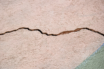Obraz premium Big horizontal winding crack on old color plastering wall. Copy space. Selective focus.