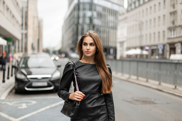 Beautiful fashionable successful woman model in trendy black clothes with a leather stylish bag...
