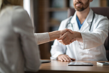 Medical Services Concept. Doctor And Female Patient Handshaking During Meeting In Clinic