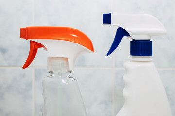 Two plastic containers with cleaning spray on a tiled background in the bathroom. Detergent...